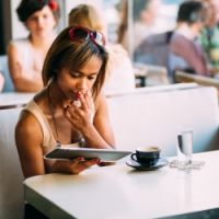 Woman looking at tablet computer in cafe