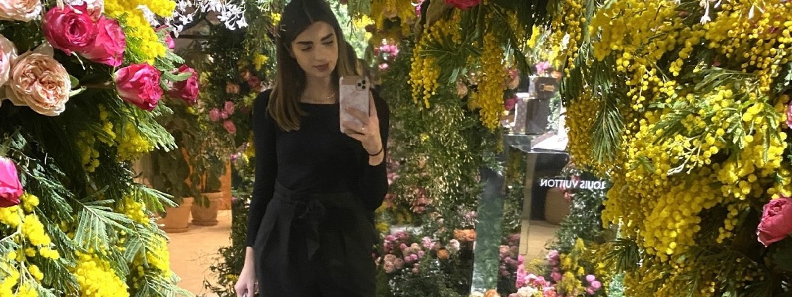Young woman taking selfie with flowers behind her